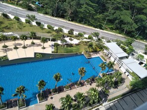 Una piscina al aire libre, sombrillas, sillones reclinables de piscina
