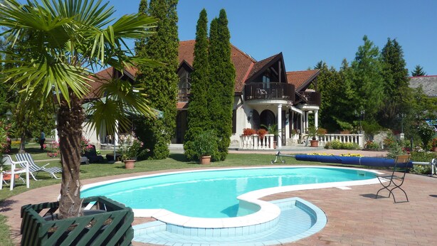 Una piscina de diseño curvo, rodeada por un patio de ladrillo.
