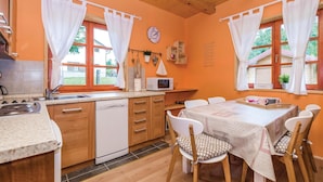 A kitchen with wooden cabinets, a dishwasher, a microwave, and a dining area with a table and chairs.