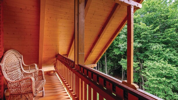 A wooden porch with a view of a forest.