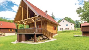 A wooden cabin with a sloped roof, a porch, and a staircase leading to the entrance.