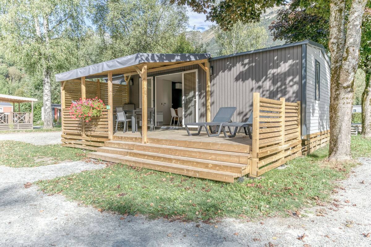A small cabin with a covered porch, a dining area, and a seating area with chairs.