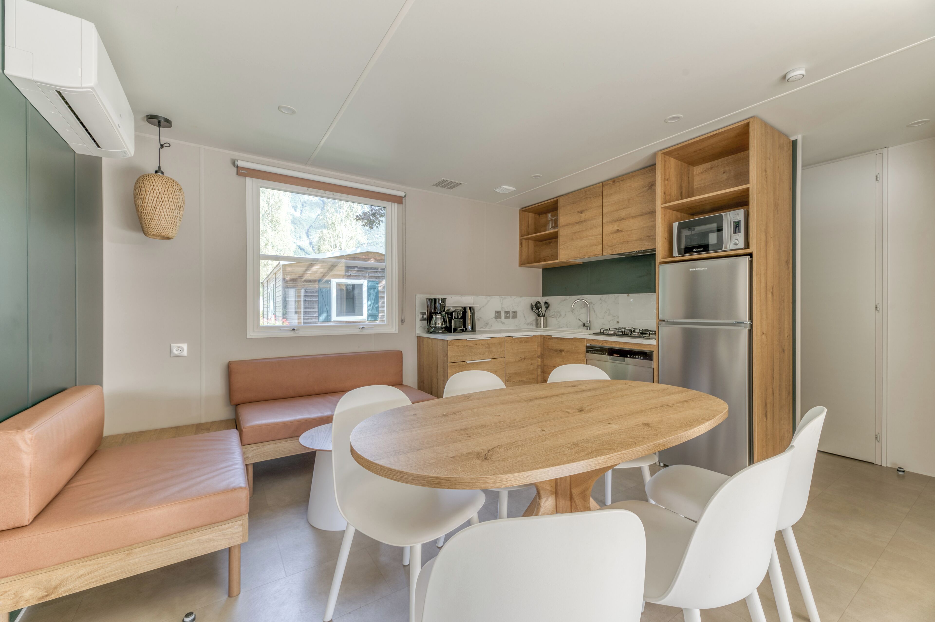 Une cuisine moderne avec une table en bois et des chaises blanches, un four encastré et un four à micro-ondes.