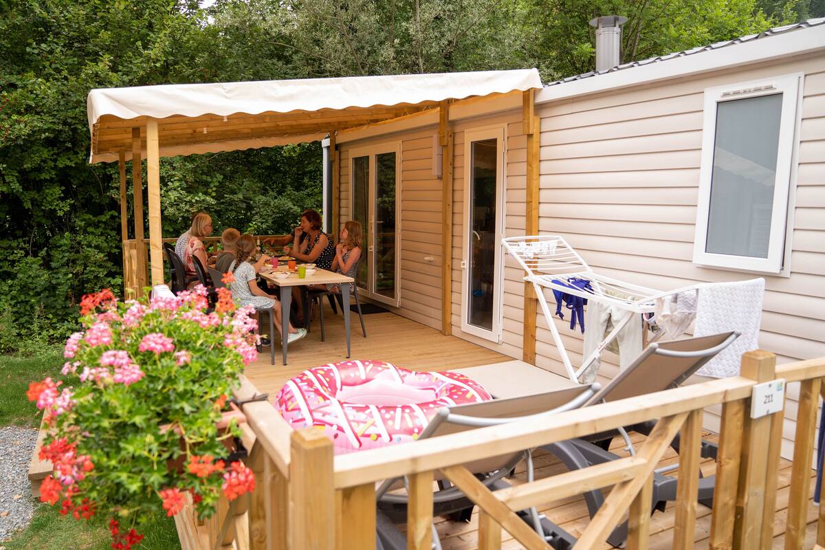 A wooden deck with a covered seating area, a pool table, and a lounge chair.