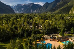 A resort with a swimming pool, surrounded by lush greenery and mountains. - Camping RCN Belledonne (Le Bourg-d'Oisans)
