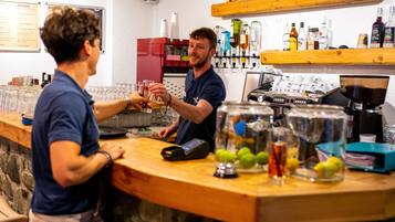 A bar area with a counter, glasses, and bottles.