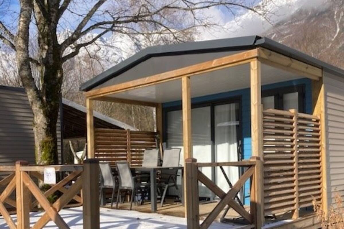 A wooden cabin with a covered porch and a staircase leading to a deck.
