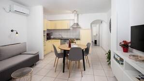 Un espace de vie compact comprenant un coin repas, une kitchenette et un téléviseur fixé au mur.