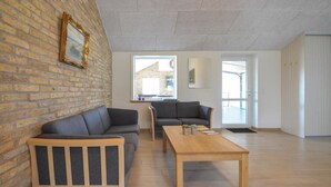 A spacious living area with a brick wall, two sofas, a wooden coffee table, and large windows.