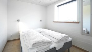 A small, clean room with a bed, a window, and a mirror.