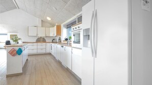 A modern kitchen with white cabinets, a wooden countertop, and a built-in oven.