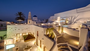 A white-washed building with a staircase leading to a rooftop terrace, featuring outdoor seating and plants. - Radiant Santorini (Santorini)