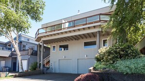 A modern two-story building with a balcony, large windows, and a garage. - Riverdell Condo feature Floor Heating and Gas Grill by RedAwning (Hood River)
