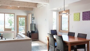 A modern kitchen with a dining area, large windows, and a TV. - Riverdell Condo feature Floor Heating and Gas Grill by RedAwning (Hood River)