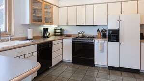 A kitchen with white cabinets, a black dishwasher, a stove, and a refrigerator. - Riverdell Condo feature Floor Heating and Gas Grill by RedAwning (Hood River)