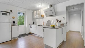 Cozinha moderna com armários brancos, micro-ondas, cafeteira e pia.