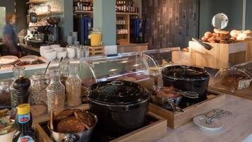 A buffet with various food items, including bread, pastries, and a coffee station.