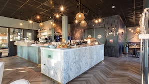 Eine moderne Bar mit einer Marmorplatte, Pendelleuchten und einem Fischgrätenparkettboden.