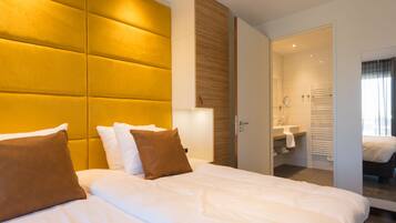 A hotel room with a large bed, a bedside table, a mirror, and a bathroom visible through an open door.