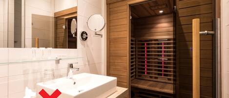 Un baño moderno con un espejo grande, un lavamanos blanco y un box de ducha de madera.