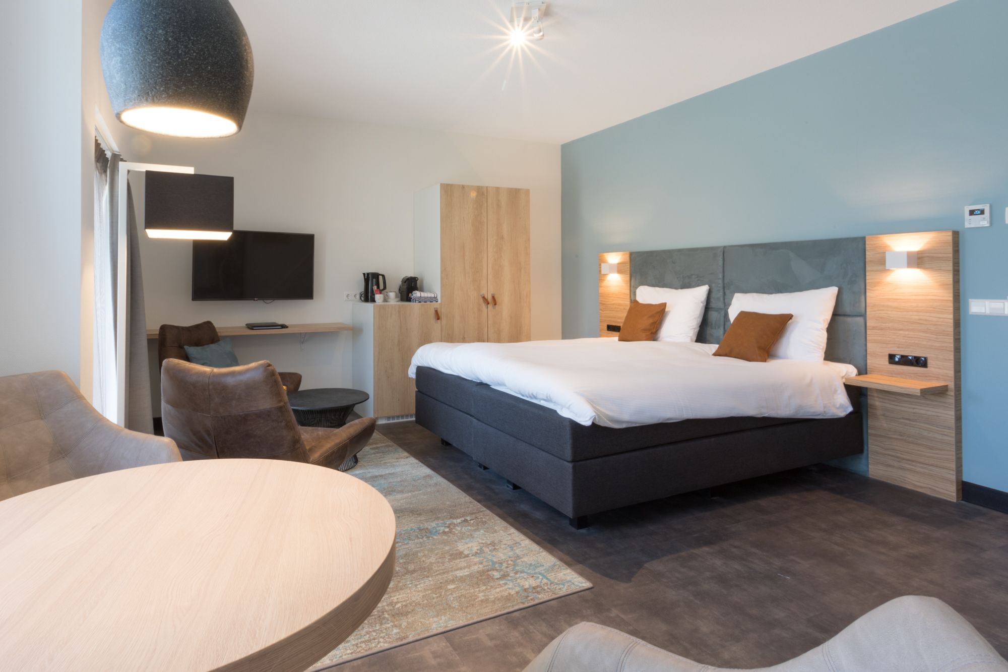 Een moderne hotelkamer met een groot bed, een bureau, een stoel en een televisie.