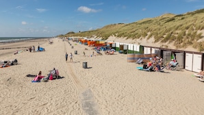 Ein Strand mit Strandkörben, Liegestühlen und entspannten Menschen.