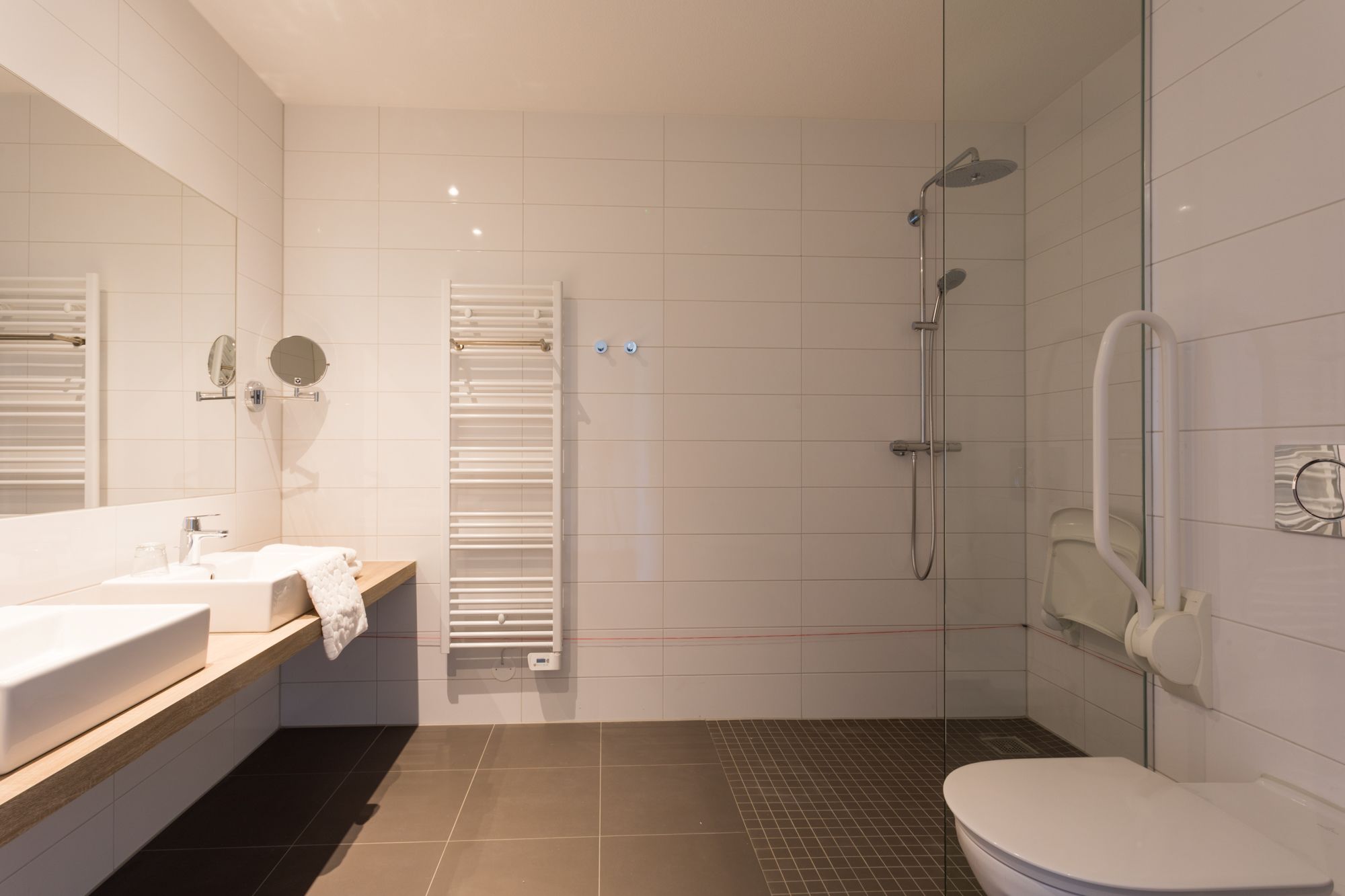 A modern bathroom with a shower, toilet, and sink.