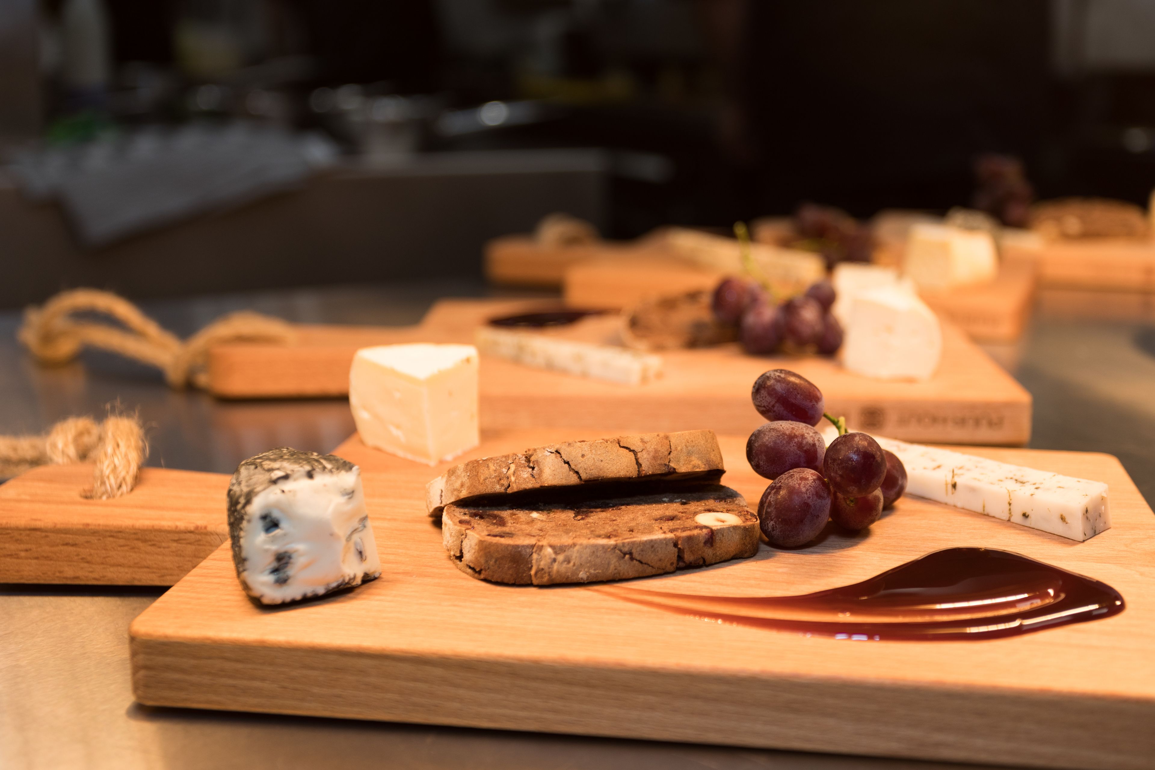 Una tabla de madera con varios quesos y uvas.