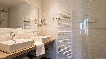 A modern bathroom with two sinks, a glass shower enclosure, and a white towel rack.