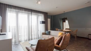 Een moderne woonkamer met een bank, stoelen, een salontafel en een eethoek.