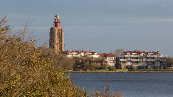 Een gebouw aan het water met een opvallende toren en meerdere woonunits.