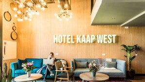 Eine Hotelhalle mit einer Holzwand, zwei Sofas, einem runden Tisch und einem Kronleuchter.