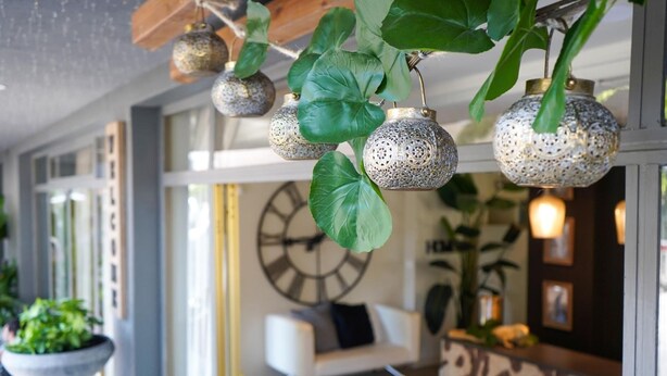Un interior moderno con faroles decorativos colgantes, un reloj de pared grande y un sofá blanco.