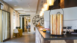 Zona de recepción de un hotel con diseño moderno, que incluye un mostrador de recepción, un reloj y una lámpara decorativa.