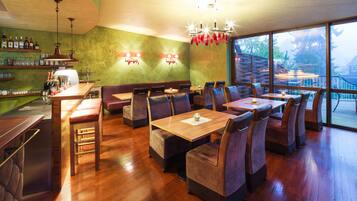 Un restaurante con mesas y asientos tipo cabina de madera, una zona de bar y un amplio ventanal con vistas al exterior.