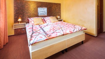 A neatly made bed with a floral bedspread, two bedside tables with lamps, and a framed picture on the headboard.