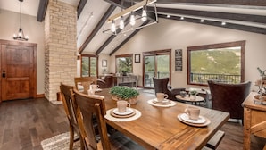 A dining area with a wooden table, chairs, and a hanging light fixture. - Breiding Upper Luxury Vacation At Windcliff 2 Bedroom Home by RedAwning (Estes Park)