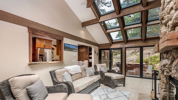 A modern living room with wicker furniture, a fireplace, and large windows overlooking a garden. - Breiding Upper Luxury Vacation At Windcliff 2 Bedroom Home by RedAwning (Estes Park)