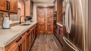 A kitchen with wooden cabinets, a stainless steel refrigerator, a sink, and a countertop. - Breiding Upper Luxury Vacation At Windcliff 2 Bedroom Home by RedAwning (Estes Park)