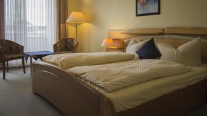 A hotel room with a double bed, a desk, a chair, and a lamp. - Hotel Am Friesenstrand (Butjadingen)