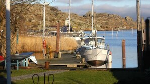A dock with a boat, a wooden pier, and a grassy area with a table and chairs. - Brännö Varv Bed & Breakfast (Branno)