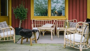 A covered outdoor seating area with wicker furniture and a potted plant. - Brännö Varv Bed & Breakfast (Branno)