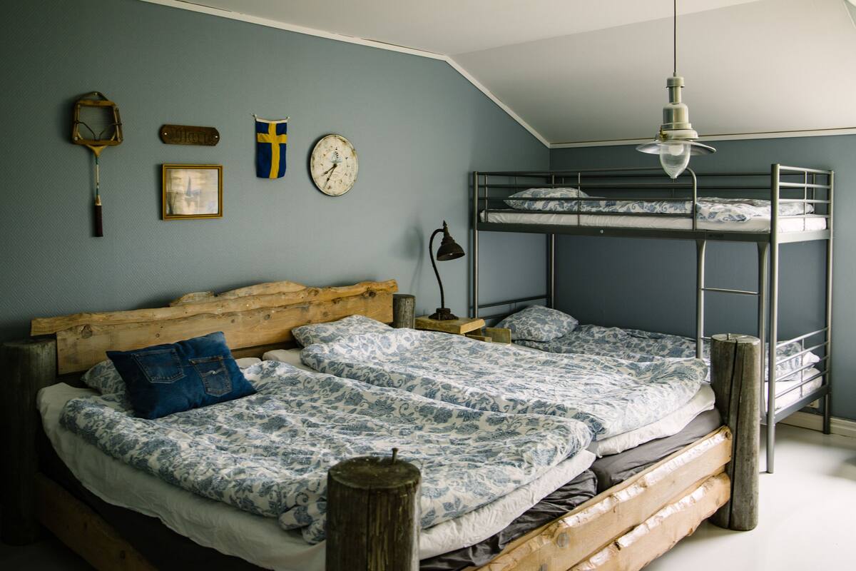 A room with a bunk bed, a wooden headboard, a wall clock, and a framed picture.