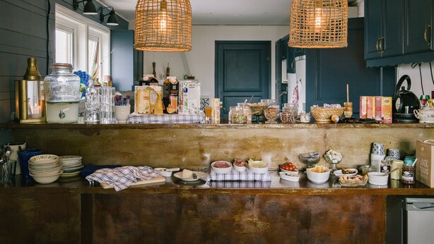 A kitchen with a rustic wooden countertop, hanging wicker light fixtures, and various kitchen items and appliances. - Brännö Varv Bed & Breakfast (Branno)