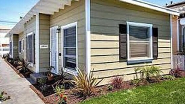Ein Bungalow mit einer Veranda und einem kleinen Garten.