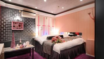 Quarto de hotel com cama, penteadeira, espelho e cômoda com armário rosa.