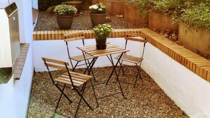 A patio with a wooden table and chairs, surrounded by potted plants and a brick wall. - Appartements Summer Break (Scharbeutz)