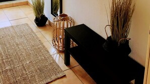 A room with a black bench, a woven rug, a potted plant, and framed artwork on the wall. - Appartements Summer Break (Scharbeutz)