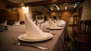 Un ambiente de restaurante con mesas dispuestas para comer, incluyendo platos, servilletas y cubiertos.