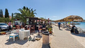Un ristorante sulla spiaggia con posti a sedere all'aperto, un cestino e vista sul mare.